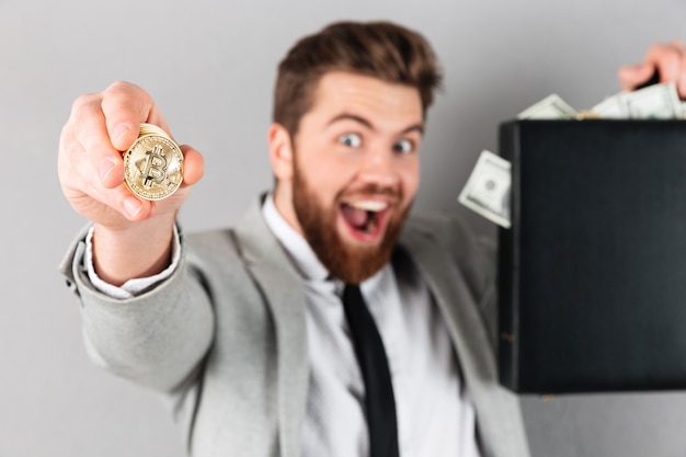 Retrato de um empresário confiante mostrando bitcoin dourado Foto gratuita