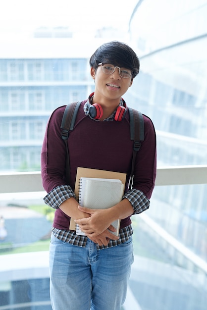 Retrato de um estudante asiático posando com livros de estudo na varanda shool Foto gratuita