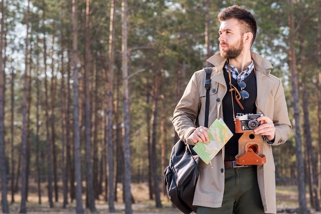 Retrato, de, um, macho, hiker, com, câmera, e, mapa, ficar, em, a, floresta Foto gratuita