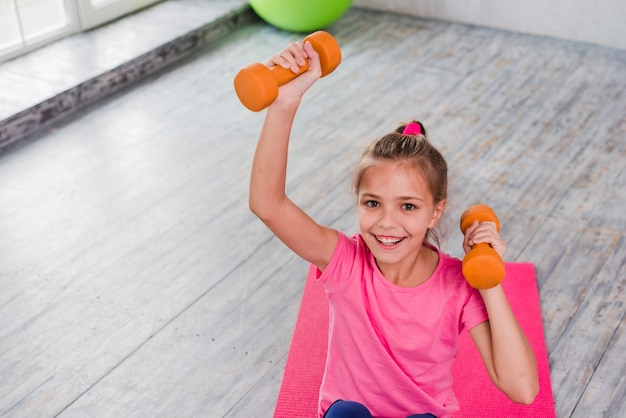 Retrato, de, um, menina sorridente, exercitar, com, um, laranja, dumbbell Foto gratuita
