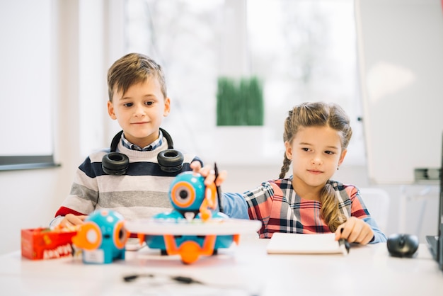 Retrato, de, um, menininho, olhar, menina, tocando, com, robotic, brinquedo Foto gratuita