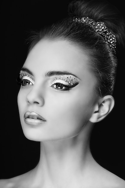 Retrato de uma jovem muito bonita com maquiagem moda isolada em preto Foto Premium