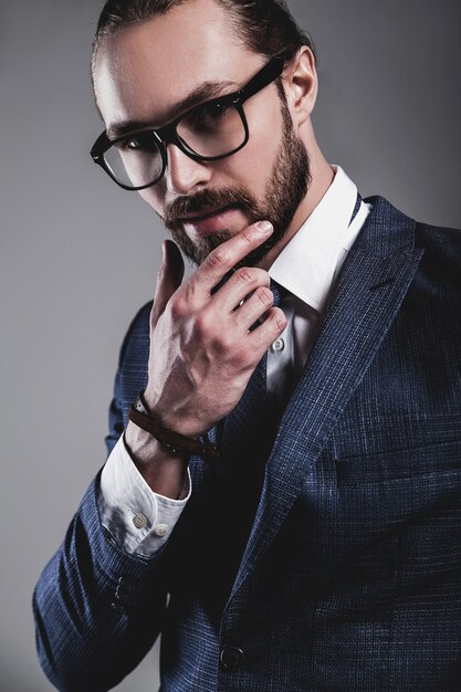 Retrato do modelo de moda bonito empresário vestido elegante terno azul com óculos Foto gratuita