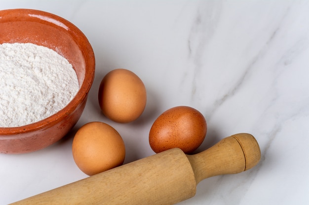 Rolo de massa, xícara de farinha e ovos Foto Premium