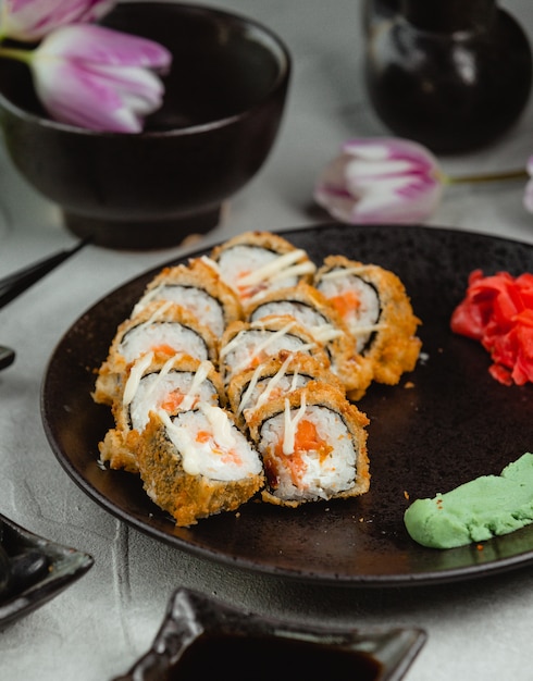 Rolos de sushi no prato blac com tulipas ao redor. Foto gratuita