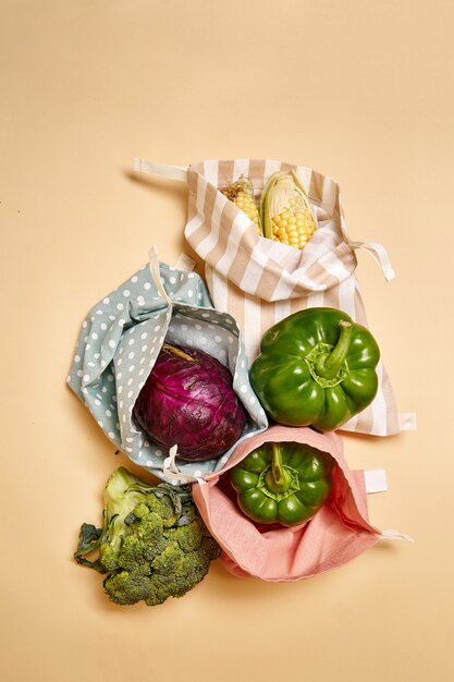 Sacos de compras de algodão de pano para mantimentos com legumes. fundo bege. sem plástico Foto Premium