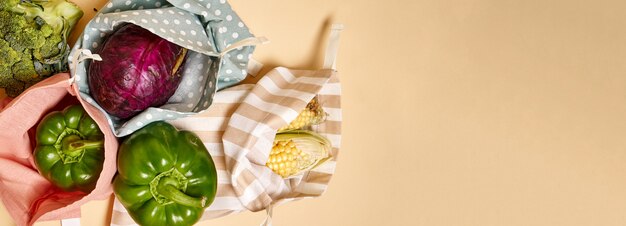 Sacos de compras de algodão de pano para mantimentos com legumes. fundo bege. sem plástico Foto Premium