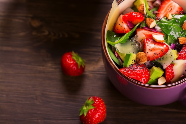 Salada de verão fresco com morango, abacate e espinafre no fundo de madeira rústico Foto Premium