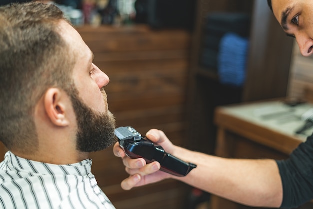 Salão de beleza para homens barbear uma barba em uma barbearia barber corta a barba com uma