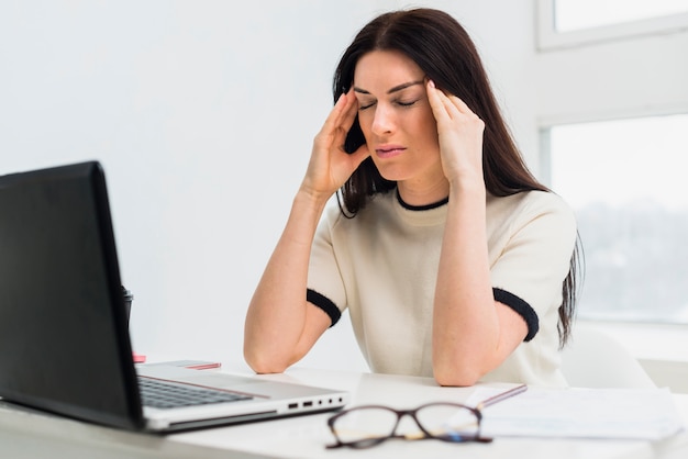 Salientou a mulher sentada à mesa com o laptop Foto gratuita