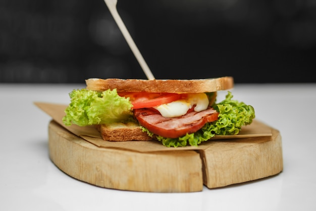 Sanduíche suculento com pão grelhado e bacon na placa de madeira Foto Premium