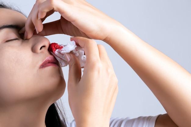 Sangue nasal, uma jovem mulher com um nariz sangrando Foto Premium