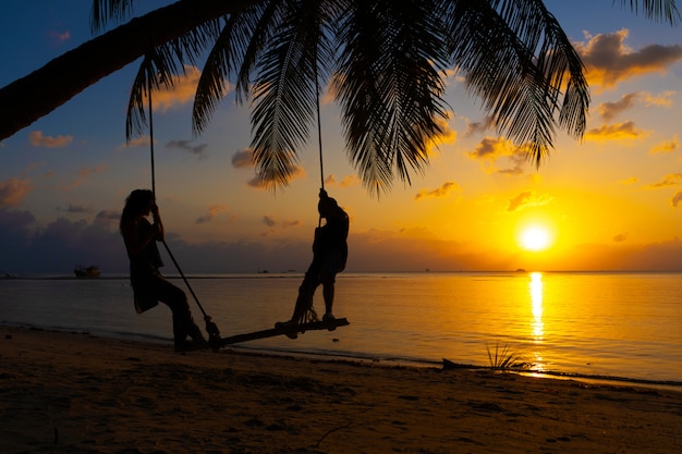 Silhueta de casal apaixonado caminha na praia durante o pôr do sol