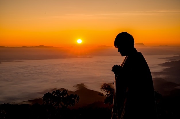 Silhueta de homem cristão rezando ao pôr do sol | Foto Premium