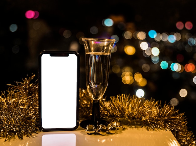 Smartphone perto de copo de bebida e ouropel Foto gratuita
