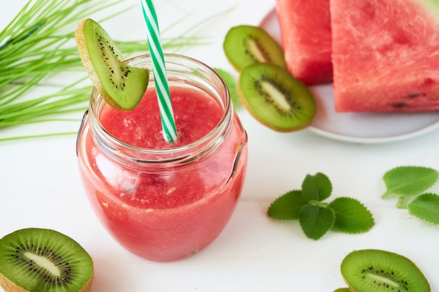 Smoothie de melancia com kiwi e hortelã em uma mesa branca Foto Premium