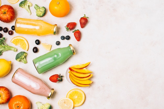 Smoothies coloridos planos e frutas com cópia espaço Foto gratuita