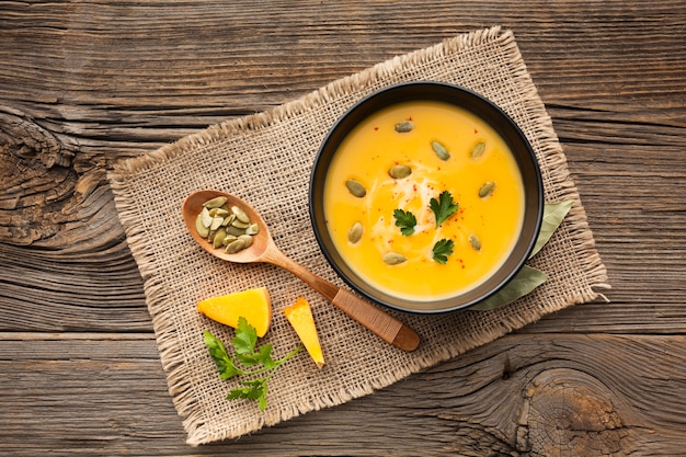 Sopa de abóbora plana leigos em tigela com colher de pau Foto gratuita