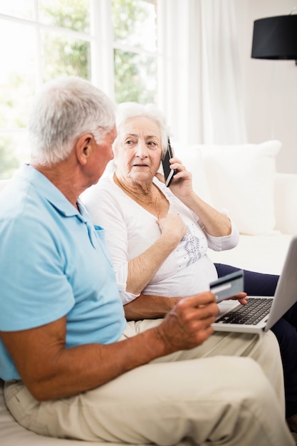 Sorrindo, par velho, usando computador portátil, e, smartphone, casa Foto Premium