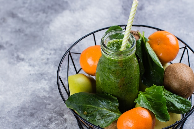 Sucos verdes ou smoothies com kiwi, espinafre, maçã verde, amêndoa cítrica e porca na cesta de metal Foto Premium
