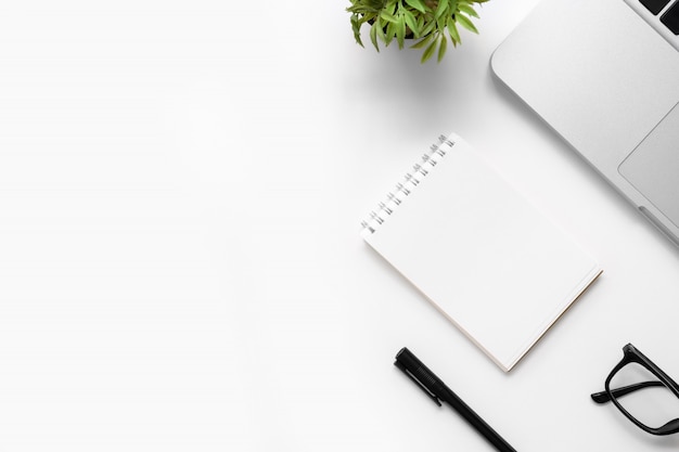 Tabela branca da mesa de escritório com caderno vazio, portátil e outros materiais de escritório. vista superior com espaço da cópia, configuração lisa. Foto Premium