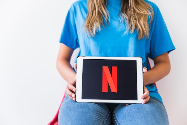 Tablet de exploração senhora irreconhecível com o logotipo da netflix Foto gratuita