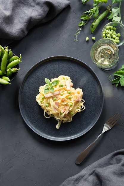 Tagliatelle da massa com creme, ervilhas e bacon. delicioso almoço mediterrânico. Foto Premium