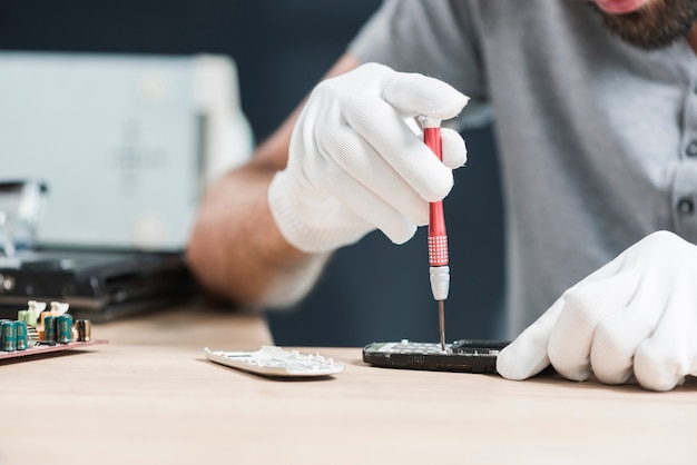 Técnico masculino, reparar, cellphone, sobre, escrivaninha madeira Foto gratuita