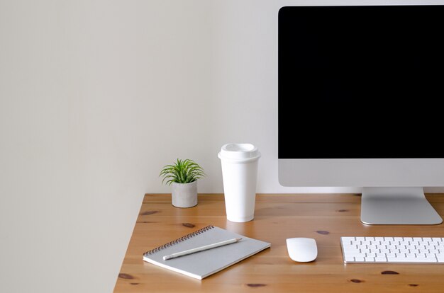 Tela de computador pessoal moderna na mesa de madeira com uma xícara de café. Foto Premium
