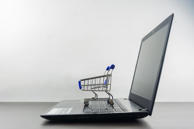 Tela em branco do computador notebook com carrinho de compras na mesa de madeira Foto Premium