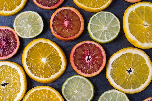 Teste padrão com fatias frescas de citrinos diferentes - laranja e limão amarelos e vermelhos, e cal. lay plana. Foto Premium