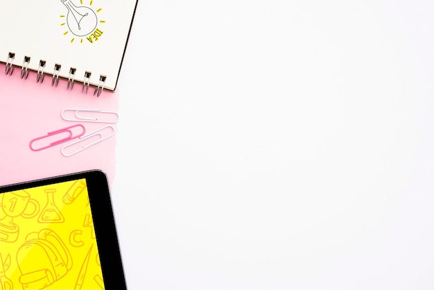Texto de ideia e mão desenhada lâmpada no bloco de notas em espiral com tablet digital sobre fundo branco Foto gratuita