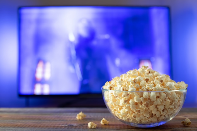 Tigela de vidro com pipoca e trabalhando tv. Foto Premium