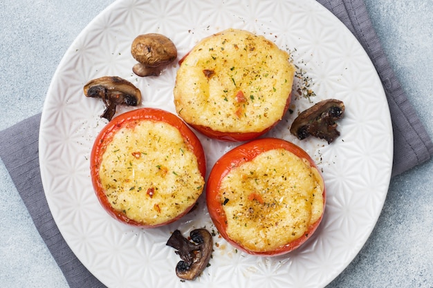 Tomate inteiro assado recheado com cogumelos e queijo com especiarias. Foto Premium