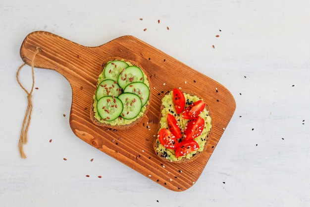 Torrada de abacate em pão integral com legumes, tomates amarelos e vermelhos Foto gratuita