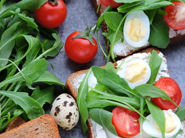 Torradas de centeio com rúcula, ovos de codorna e tomate cereja. Foto Premium