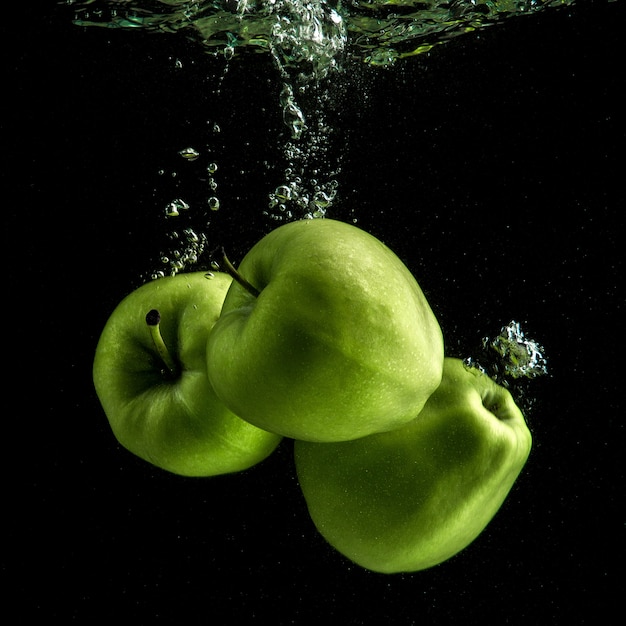 Três maçãs verdes frescas na água Foto gratuita
