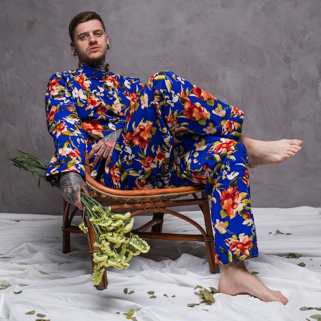 Triste, relaxado, homem jovem, sentar-se cadeira, segurando, limonium, flor, em, mão Foto gratuita
