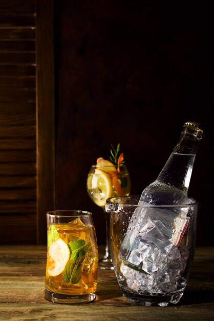 Uísque com base cocktail com balde de gelo de vidro no backgorund de madeira escura Foto Premium