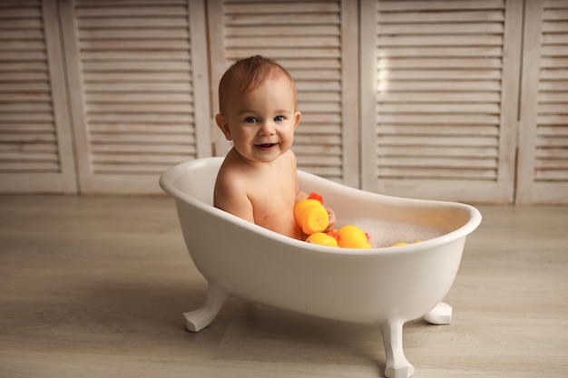 Um Bebê De 11 Meses Tomando Banho Em Uma Banheira De Bebê Branca Com Patinhos De Borracha Foto