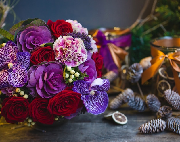 Um buquê de rosas vermelhas, flores cor de rosa e roxas com folhas na mesa de natal Foto gratuita