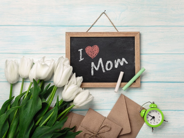 Um buquê de tulipas brancas com placa de giz e envelopes em placas de madeira azuis. dia das mães Foto Premium