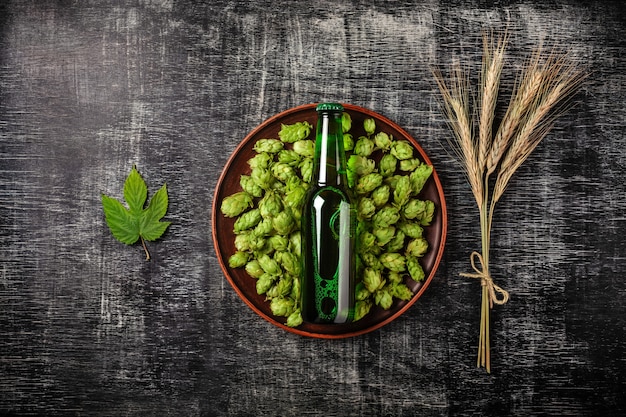 Um, garrafa cerveja, ligado, um, verde, pulo, em, um, prato, com, spikelets, e, pulo, folha, de, trigo, experiência, um, pretas, riscado, junta giz Foto Premium