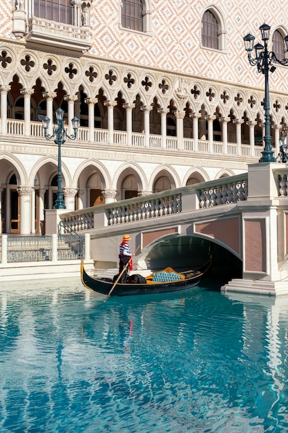 Um gondoleiro no venetian hotel and casino com um remo flutuando em um canal em uma gôndola em las vegas, nevada, eua. Foto Premium