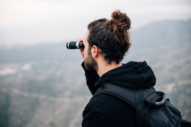 Um, macho, hiker, com, seu, mochila, olhar, vista montanha, através, binocular Foto gratuita