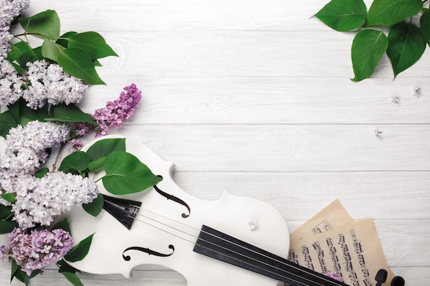 Um ramalhete dos lilacs com violino e folha de música em uma tabela de madeira branca. top wiev com espaço para o seu texto. Foto Premium