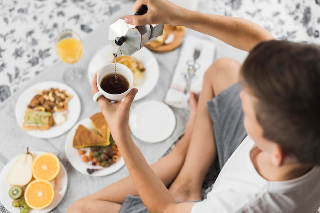 Um, visão aérea, de, um, menino, chá torrencial, em, copo, com, café manhã tabela Foto gratuita