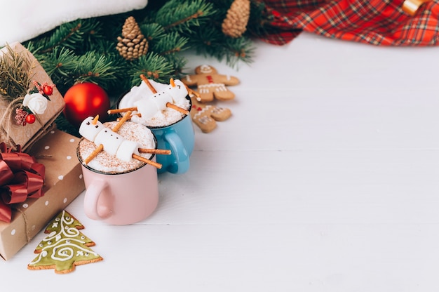 Uma caneca com chocolate quente em uma mesa de madeira com um homem de marshmallow que está descansando em uma caneca Foto Premium