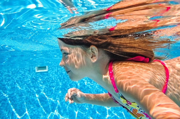 Uma Criança Nadando Debaixo Dágua Na Piscina Uma Menina Feliz E Ativa Mergulha E Se Diverte 7741