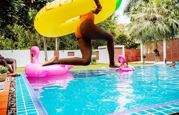 Uma mulher africana pulando na piscina com bóia inflável e aproveitando o horário de verão Foto Premium